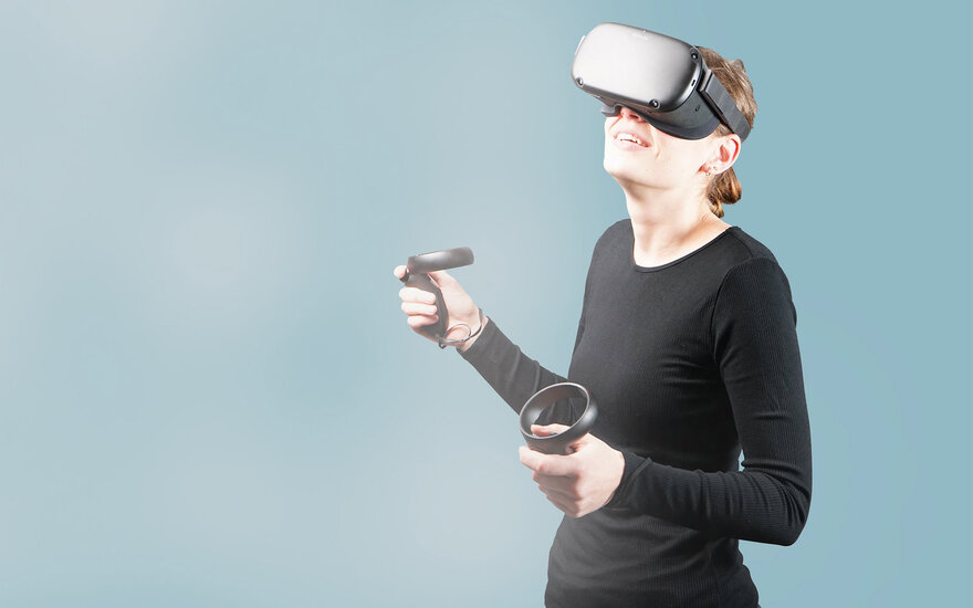 Eine Frau mit VR-Brille und Joysticks.