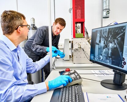 Zwei Mitarbeiter der Forschungseinrichtung ZeWiS arbeiten an einem Rasterelektronenmikroskop.