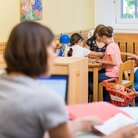 Eltern-Kind-Carell in der Bibliothek, zwei Studentinnen lernen und die Kinder spielen