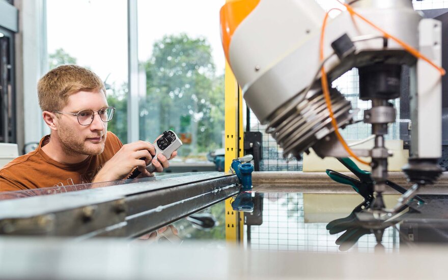 Ein Student stellt die Hochdruck-Wasserstrahlschneidanlage im Labor für Produktionstechnik ein.