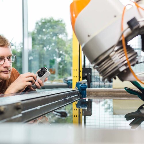 Ein Student stellt die Hochdruck-Wasserstrahlschneidanlage im Labor für Produktionstechnik ein.