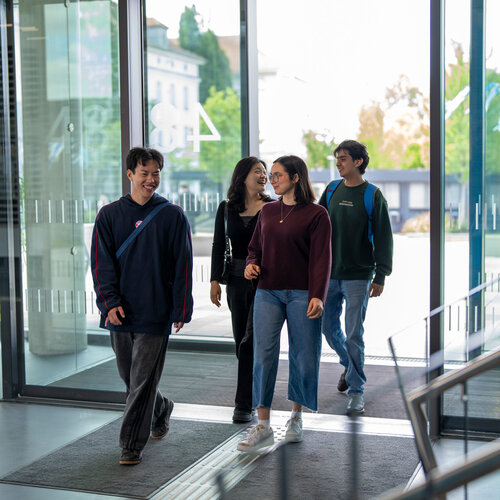 Students entering building 48 through glass dors.