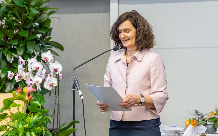 Frau spricht am Mikrophon mit Skript in der Hand