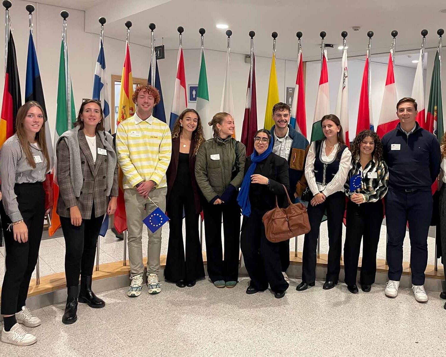 Eine Gruppe von Studierenden im Europäischen Parlament mit Flaggen im Hintergrund