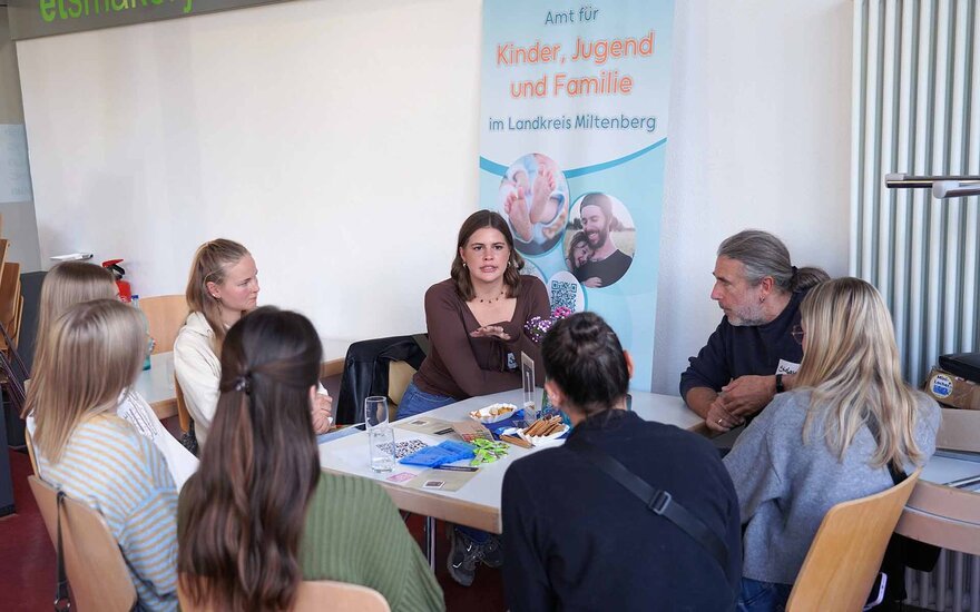 5 Studentinnen und 2 Fachkräfte sitzen an einem Tisch in der Mensa und sind im Gespräch