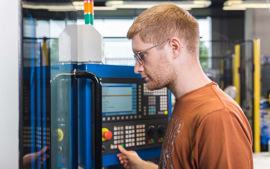 Ein Student bedient eine CNC-Schrägbettdrehmaschine im Labor für Produktionstechnik.