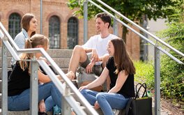 Studierende auf einer Treppe auf dem Campus-Gelände