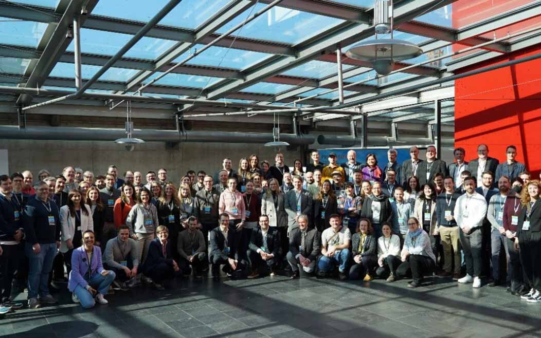 Gruppenfoto mit allen Teilnehmenden im Foyer der Hochschule München unter dem Glasdach