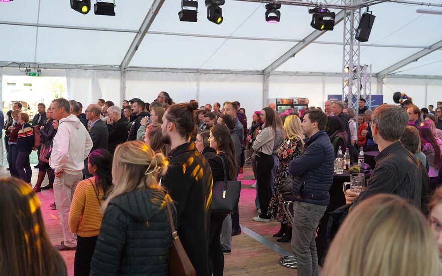 Große Anzahl an Personen, die mit Blick auf die Bühne im Festzelt stehen