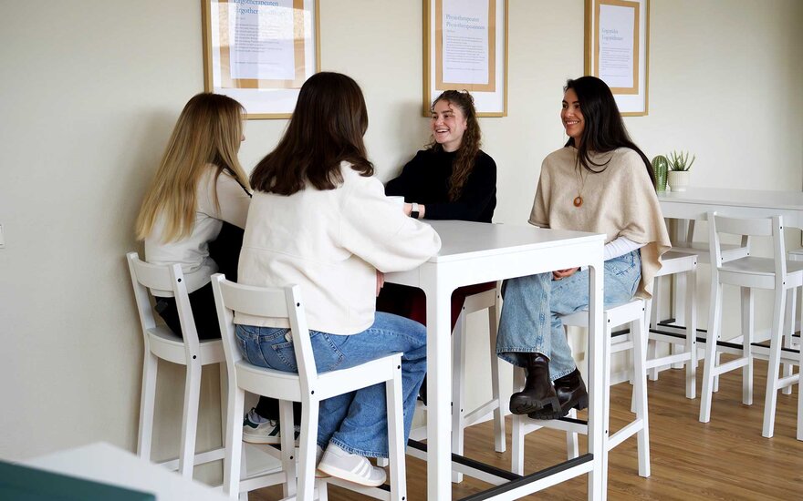 Vier Auszubildende sitzen gemeinsam an einem Tisch und unterhalten sich.