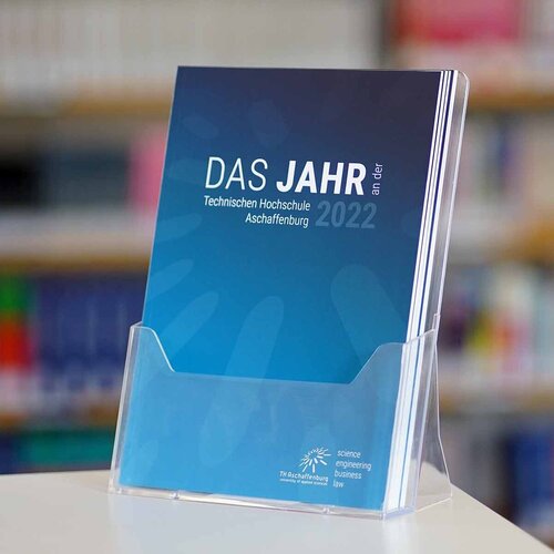 Blaues Cover des Jahresberichtes 2022 vor Bücherregal im Hintergrund