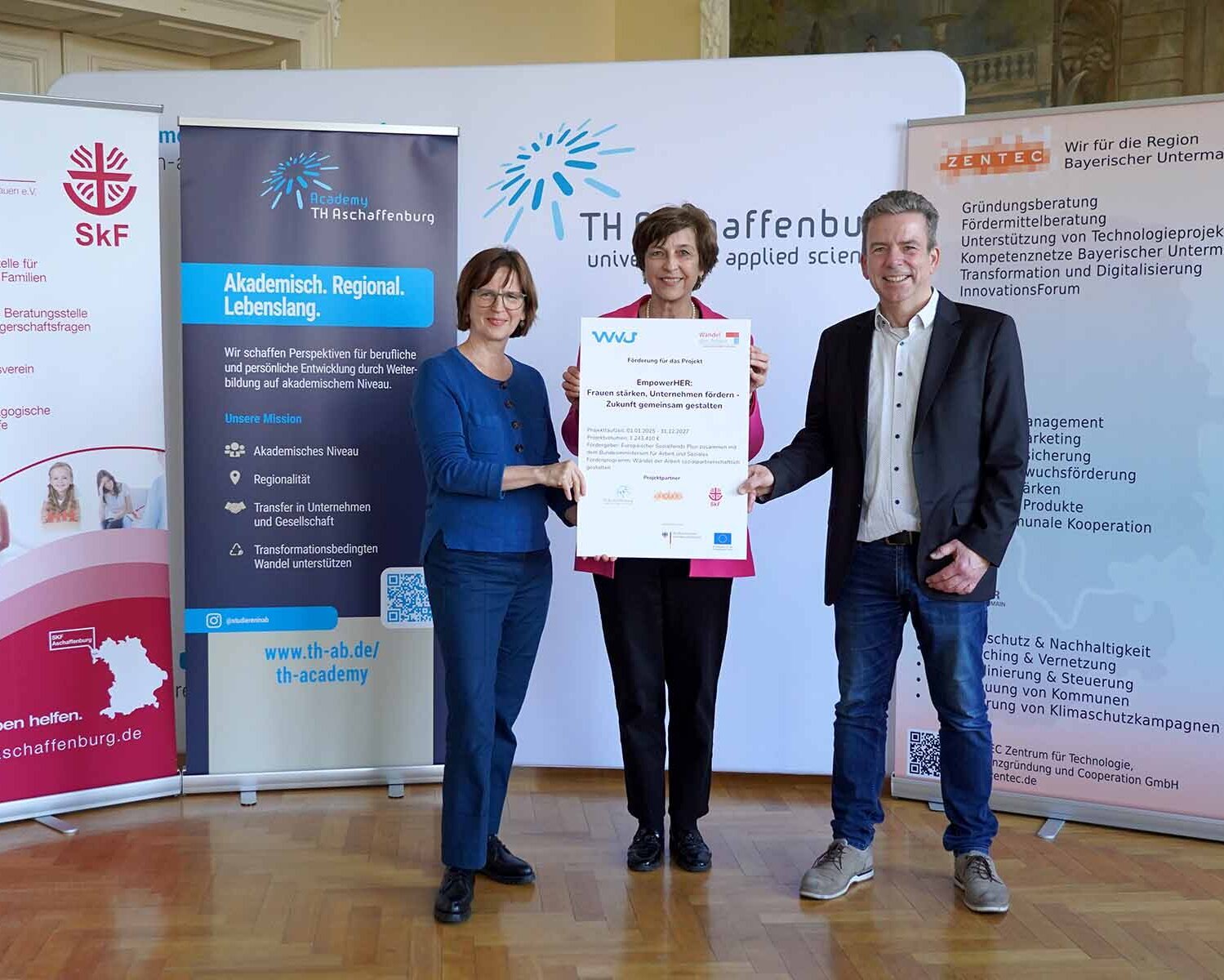 Vorsitzende des SkF, TH-Präsidentin mit Tafel mit Logos und Fördersumme und Zentec-Geschäftsführer vor TH-Wand und Roll-ups 