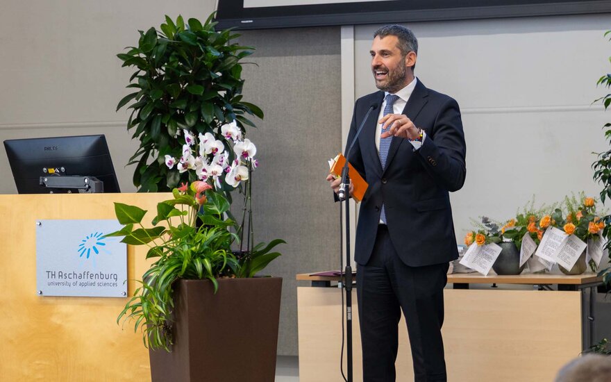 Landrat steht lächelnd am Mikrophon neben dem Rednerpult