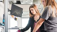 Two students work on a digital production process with a learning assistance system.