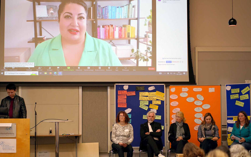 Personen und Leinwand während Podiumsdiskussion