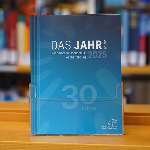 Jahresbericht 2025 mit Frontalansicht des blauen Covers im Bücherregal 