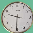 Silberne runde Uhr mit weißen Ziffernblatt und schwarzen Zeichen auf türkis grünem Hintergrund zeigt neun Uhr dreißig