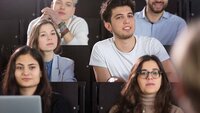 Studierende sitzen im Hörsaal und hören Professorin zu
