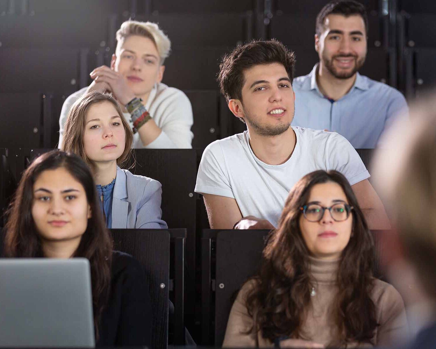 Studierende sitzen im Hörsaal und hören Professorin zu