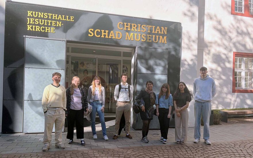 Acht Studierende stehen nebeneinander vor dem Eingang des Museums