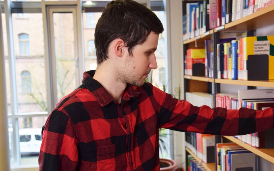 Student greift in Bücherregal in Bibliothek 