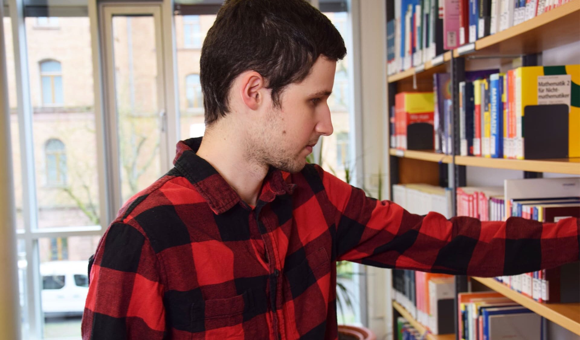 Student greift in Bücherregal in Bibliothek 