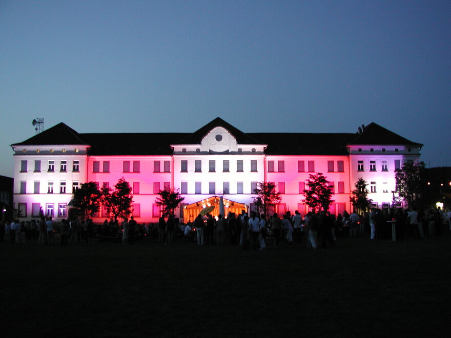 Ein großes Gebäude, dass bei Nacht in bunten Farben beleutet ist.