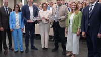 Drei Frauen und vier Männer stehen im Hörsaal, zwei der Männer halten große Schlüssel in der Hand