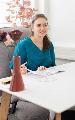 Frau schwanger im Gespräch mit Hebamme, Ärztin, Arzthelferin am Tisch 