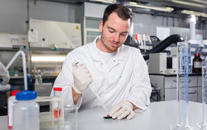 A laboratory employee applies liquid to a sensor using a laboratory pipette.