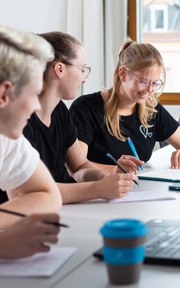 Mehrere Studierende während einer Gruppenarbeit mit Laptop und TH AB To-Go Becher.