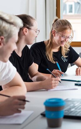 Mehrere Studierende während einer Gruppenarbeit mit Laptop und TH AB To-Go Becher.