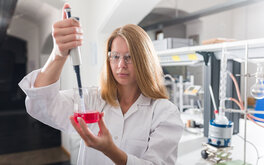 Eine Studentin mit einer Pipette und einem Becherglas mit Flüssigkeit in einem Labor an der TH Aschaffenburg.