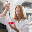 Eine Studentin mit einer Pipette und einem Becherglas mit Flüssigkeit in einem Labor an der TH Aschaffenburg.