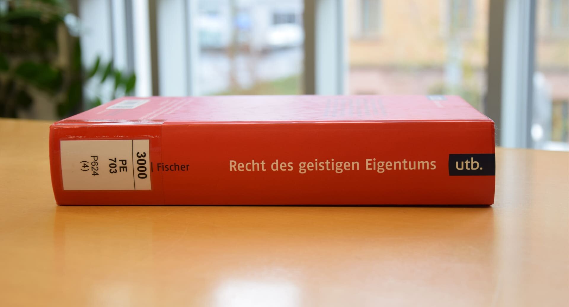 Rotes Buch auf Tisch liegend in Bibliothek, Recht des geistigen Eigentums