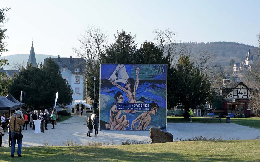 Ausstellungskubus mit Gemälden von Kirchner an der Außenwand und Besuchern der Eröffnung in Königstein