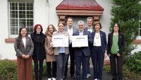 Gruppenbild mit 9 Personen (Spender, Hochschulleitung und Studierende) vor Gebäude 21