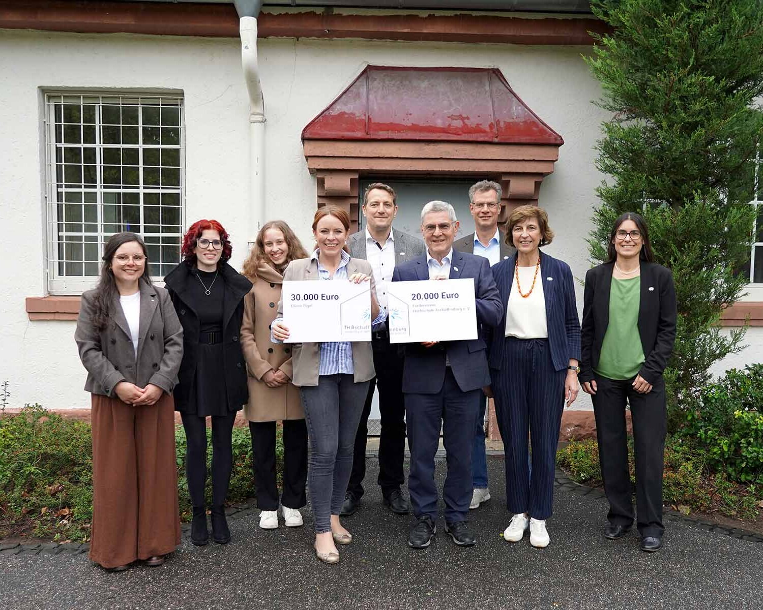 Gruppenbild mit 9 Personen (Spender, Hochschulleitung und Studierende) vor Gebäude 21