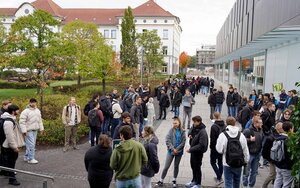 Eine große Gruppe neuer Studierender läuft zwischen zwei Gebäuden über den Campus der Hochschule