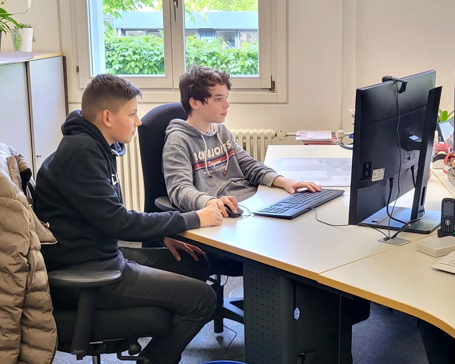 Zwei Jungs sitzen am Boys day in der Bibiliothek an einem Computer.