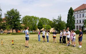 Laboringenieur Sebastian Zeising steht auf der Campuswiese und erklärt den Schülerinnen und Schülern das anstehende Experiment mit der kleinen Rakete, die hinter im steht