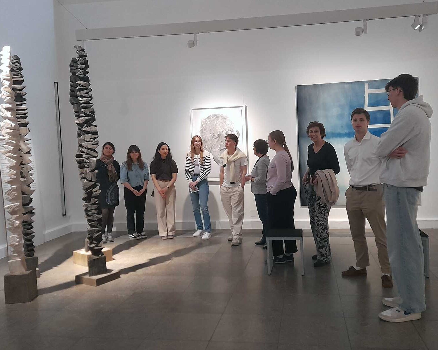 Studierende stehen im Halbkreis mit Präsidentin vor einem Kunstwerk