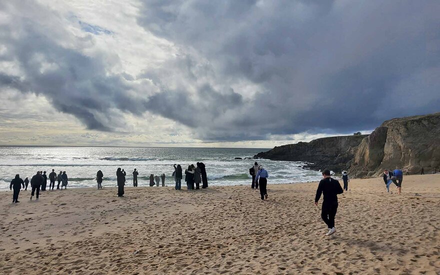 Strand, Meer, laufende Menschen bei bewölktem Himmel