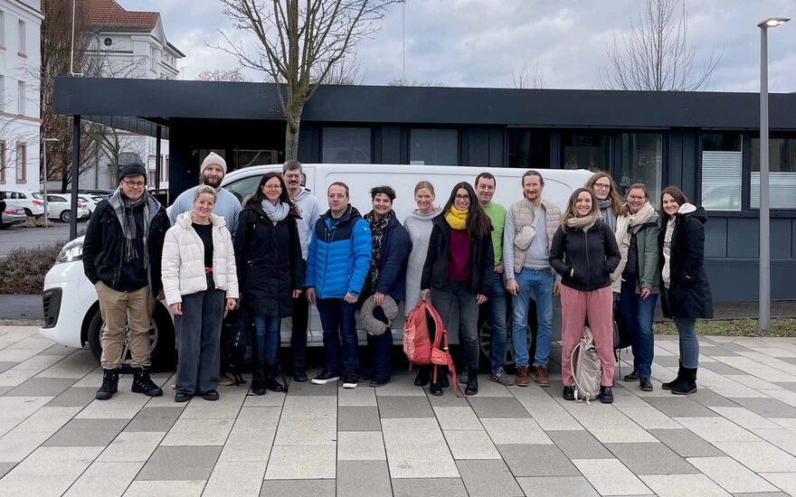 Eine Menschengruppe mit Gepäck posiert vor einem Autobus. 