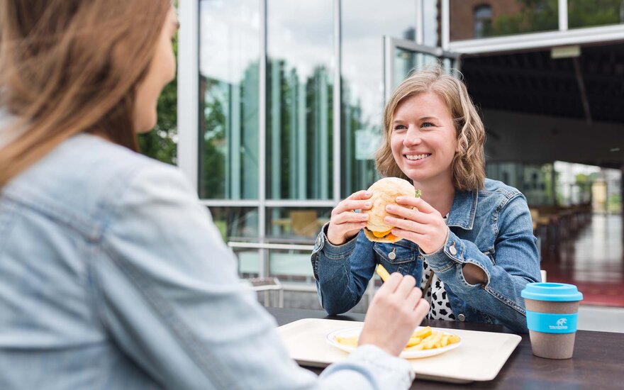 Studentin isst Burger vor der Mensa