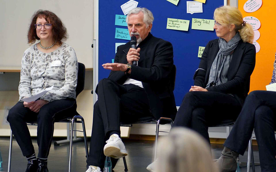 Drei sitzende Personen während Podiumsdiskussion