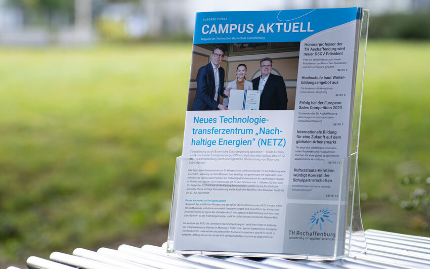 Magazin im Aufsteller vor grünem Hintergrund einer Campuswiese