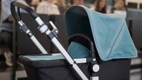 Kinderwagen steht im Hörsaal vor ansteigenden Reihen mit Studierenden