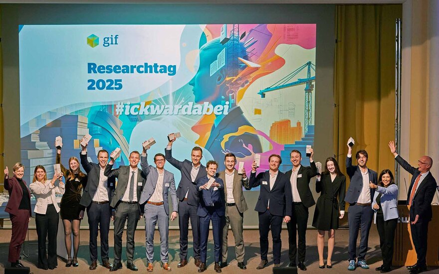 Gruppe vor einer Leinwand mit der Aufschrift Researchtag 2025. Sie halten je mit einem Arm ihre Preise in die Höhe. 