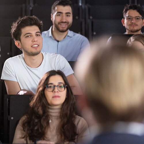 Mehrere Studierende in einem Hörsaal während einer Vorlesung in Frontalansicht